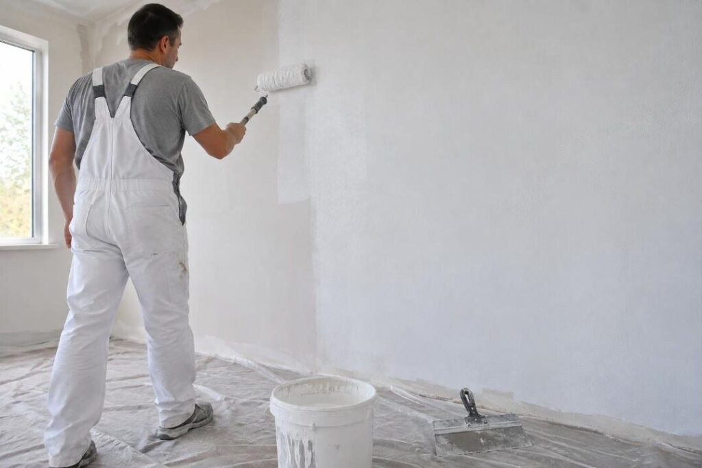 Peintre appliquant une sous-couche au rouleau sur un mur en plâtre fraîchement enduit